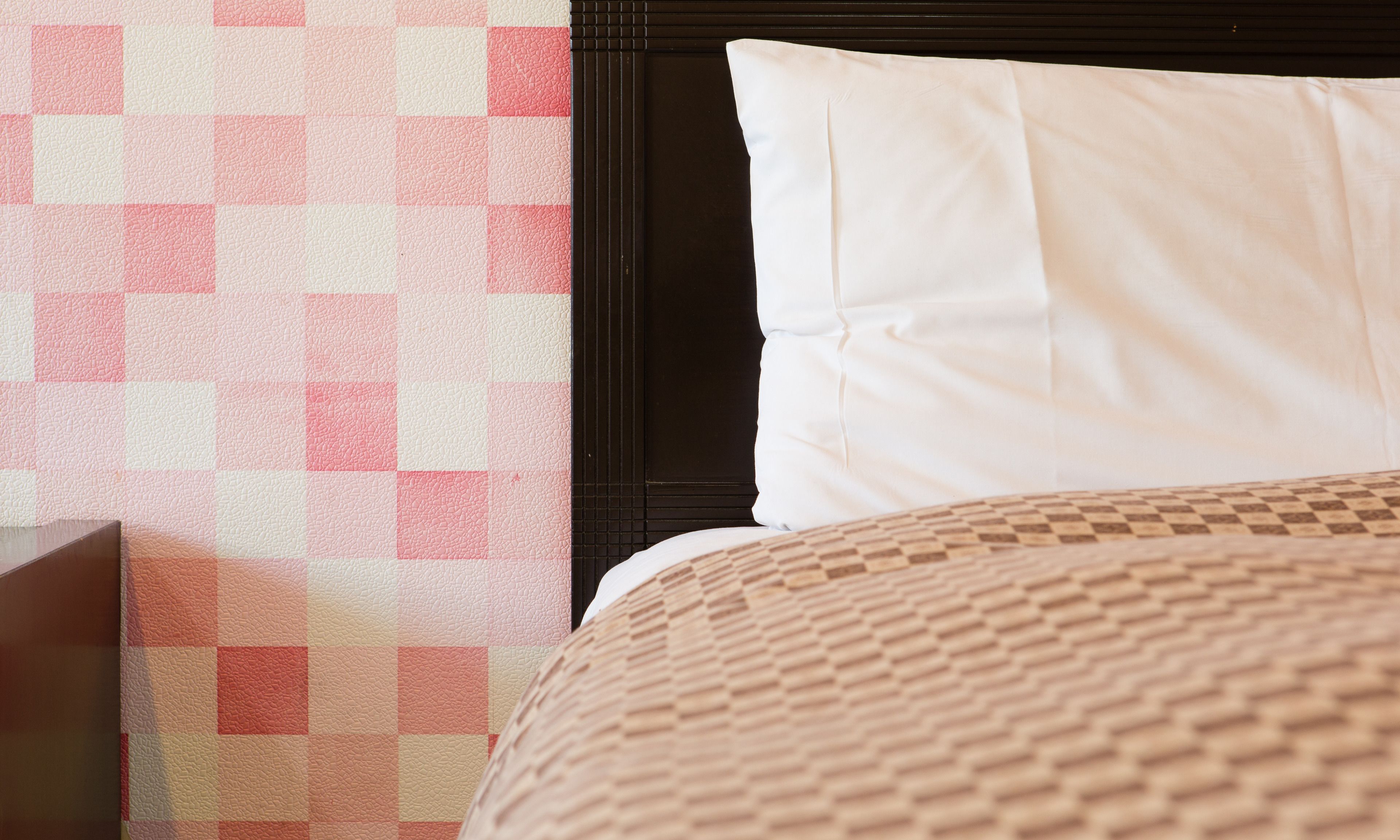 A bed with a checkered headboard and a white pillow.