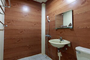 Ein Badezimmer mit Holzwänden, einem weißen Waschbecken, einem Spiegel und einer Toilette.