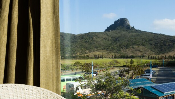 A view of a mountain with a parking lot and a building with solar panels in the foreground. - Dajenshan Hotel (Hengchun)
