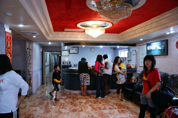 A lobby with a reception desk, a chandelier, and a clock on the wall.