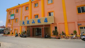A building with a sign reading "FamilyMart" and another sign with Chinese characters. There are several scooters and a bicycle parked in front. - Dajenshan Hotel (Hengchun)