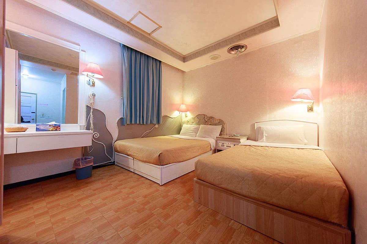 Ett hotellrum med två sängar, ett skrivbord och en spegel.