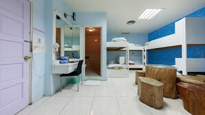 A room with bunk beds, a desk with a chair, a mirror, and a small table with stools. - Dajenshan Hotel (Hengchun)