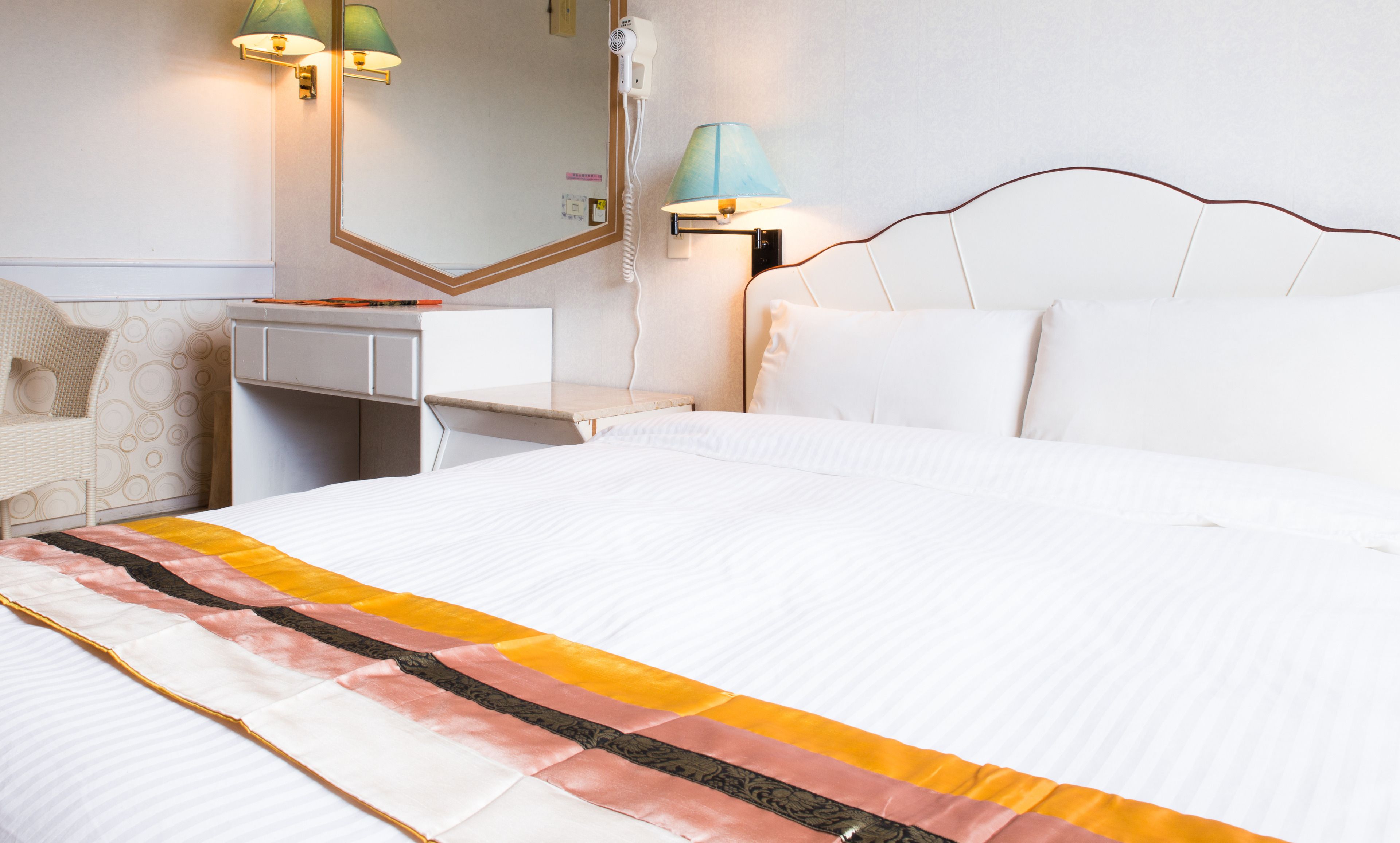 Une chambre d’hôtel bien rangée, avec un lit, un bureau et une chaise.