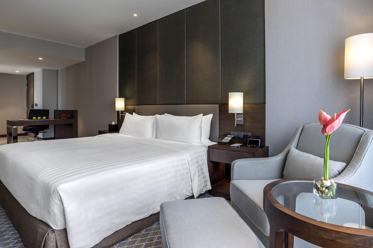 Ein Hotelzimmer mit einem großen Bett, einem Schreibtisch, einem Stuhl, einem kleinen Tisch und einer Lampe.