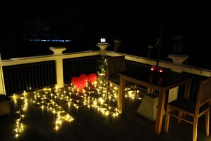 A balcony with string lights, a wooden table, and chairs. - Misty Hills Villa Kadugannawa  (Udunuwara)