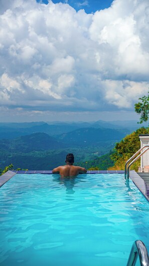 A person in a swimming pool with a view of mountains and cloudy sky. - Misty Hills Villa Kadugannawa  (Udunuwara)