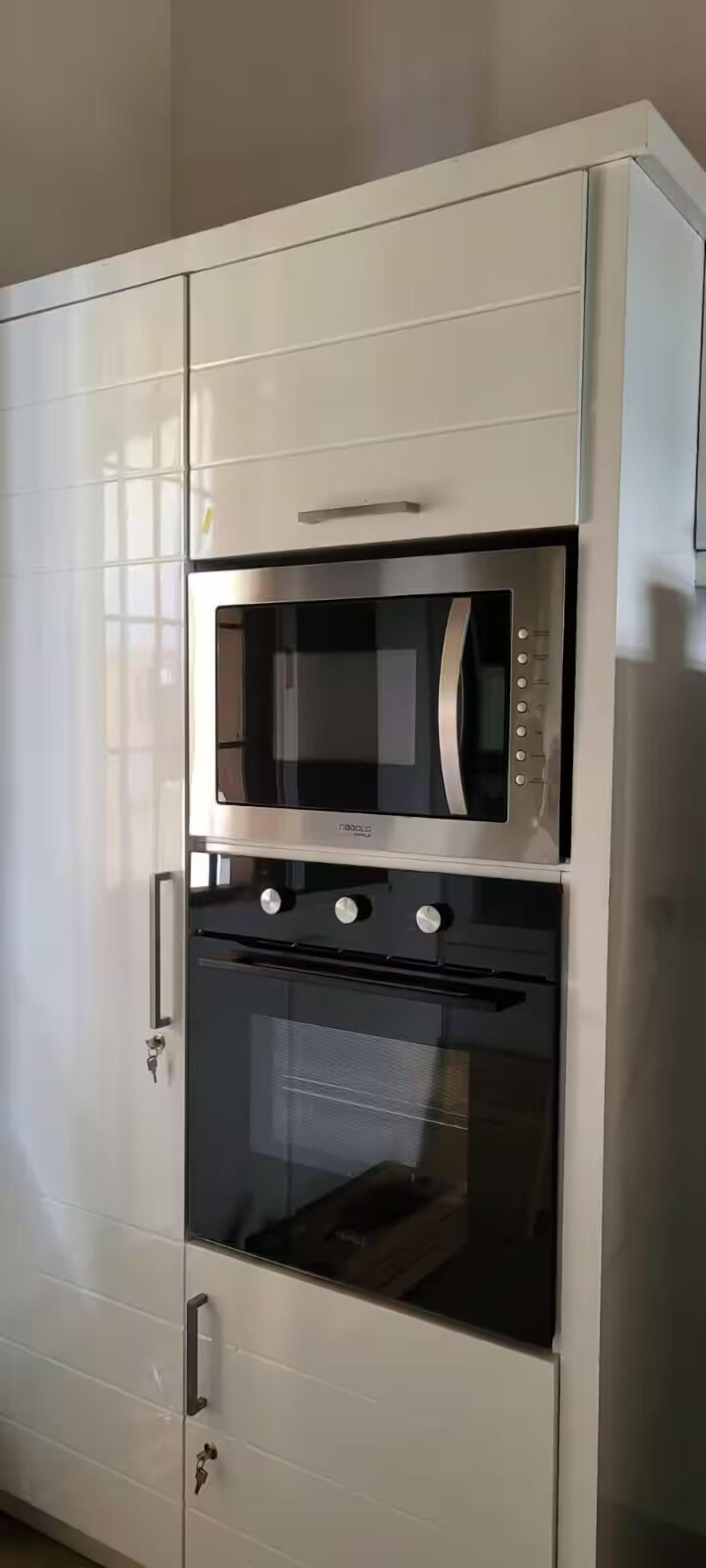 A white kitchen with a built-in microwave and oven.