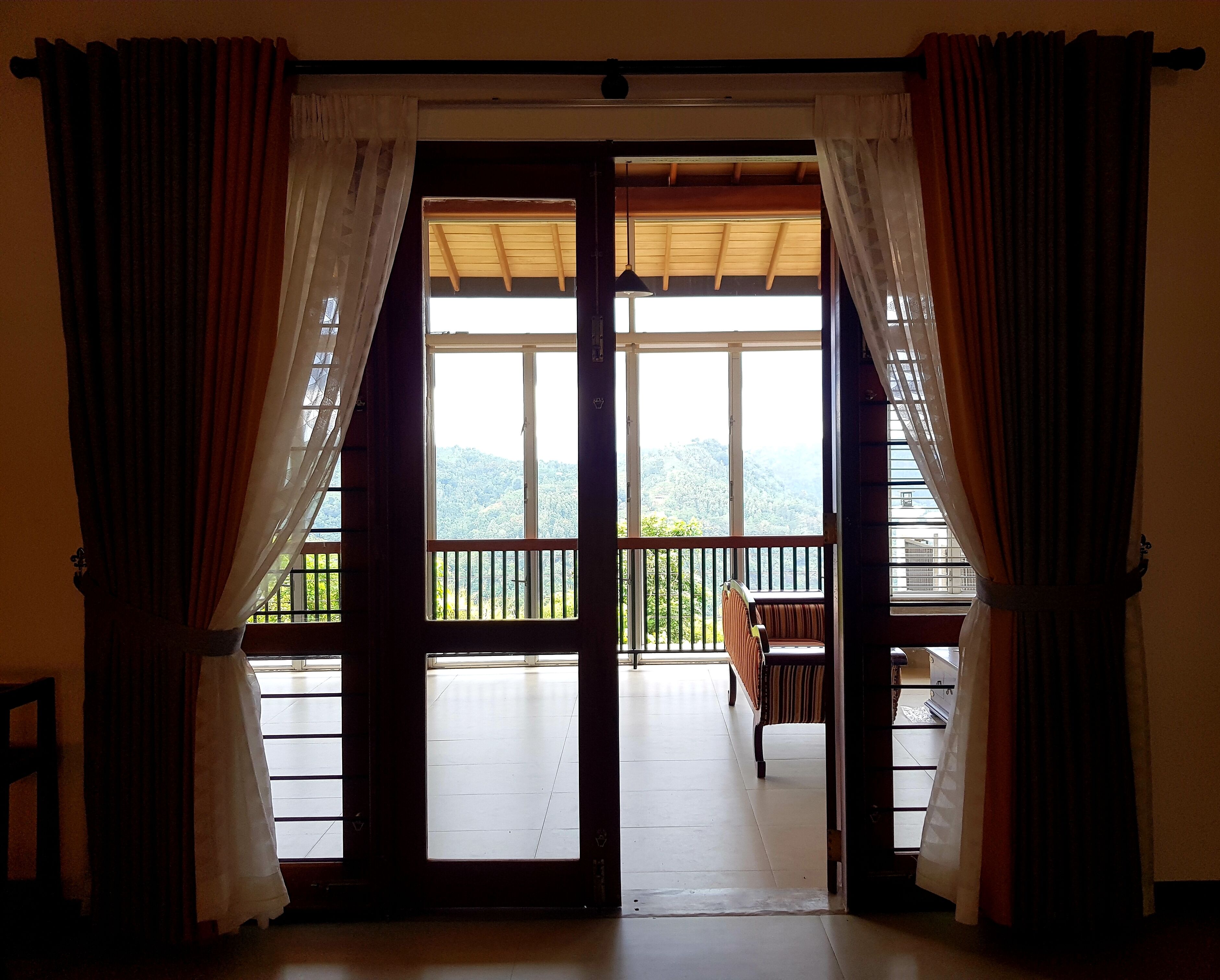 A room with a large sliding glass door leading to a balcony with a view of a mountainous landscape.