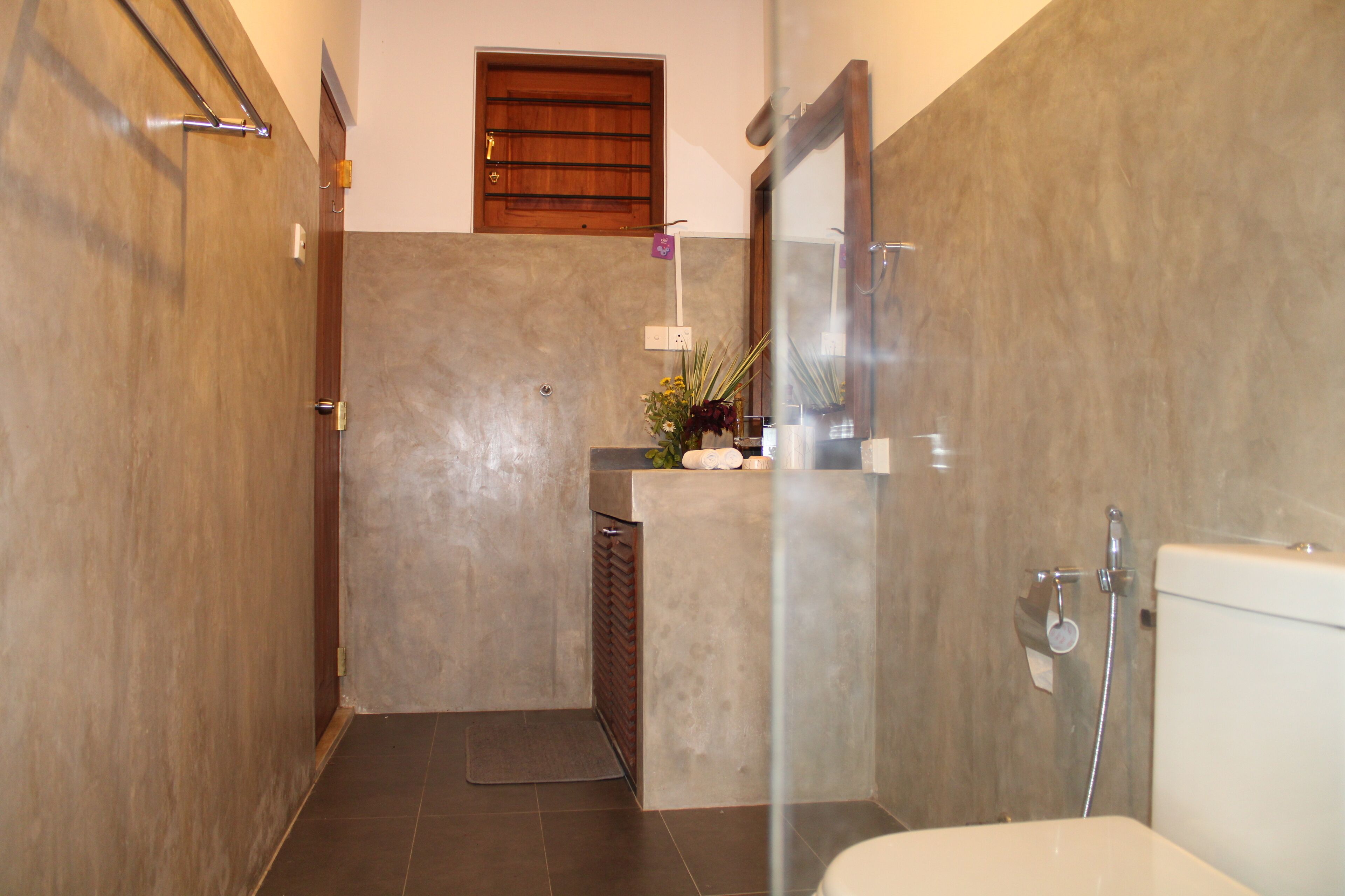 A bathroom with a shower, toilet, and a small sink area.
