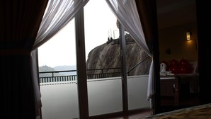 A room with a large window overlooking a rocky landscape and a balcony. - Misty Hills Villa Kadugannawa (Udunuwara)