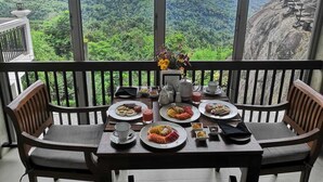 A balcony with a table set for breakfast, overlooking a mountainous landscape. - Misty Hills Villa Kadugannawa (Udunuwara)