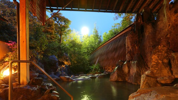 A serene indoor water feature with a wooden structure, rocks, and a thatched roof. - Hotel Parens Onoya (Asakura)