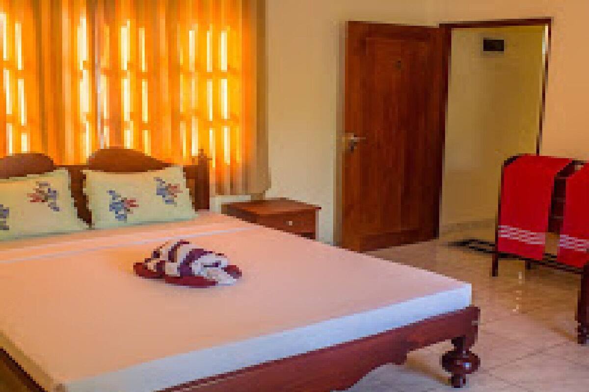 Un dormitorio con cama, almohadas, una mesita de noche y una puerta.