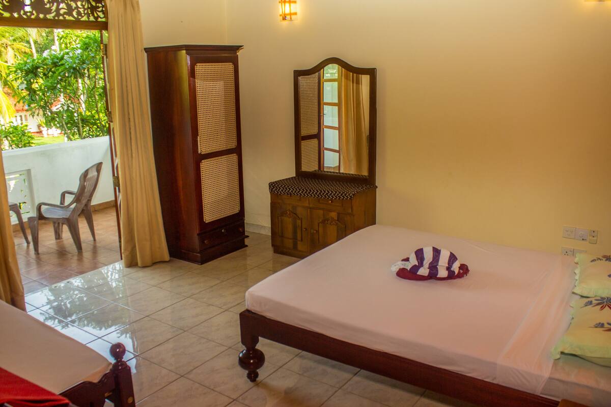 Habitación con cama, armario de madera, espejo, silla y vistas a zonas verdes.