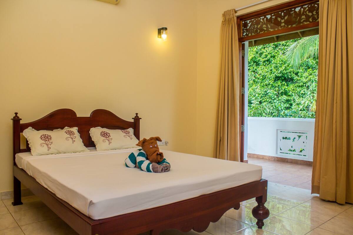 Una cama bien hecha con un cojín decorativo, un peluche y una lámpara de pared.