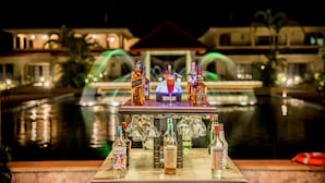 Zona de bar con vistas a la piscina, mostrando diferentes botellas y vasos.