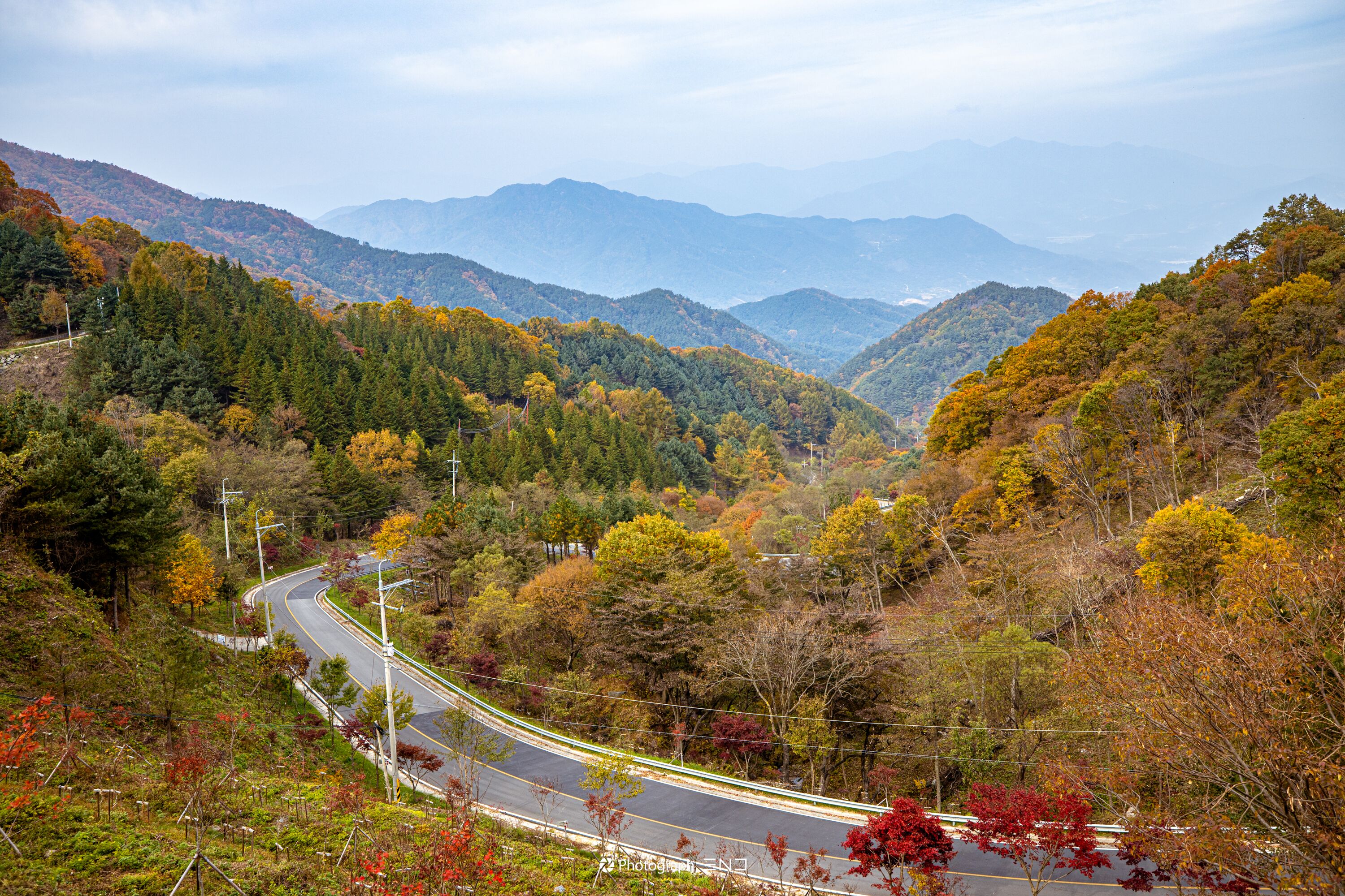 A winding road through a mountainous area with autumn foliage.