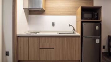 A modern kitchen with wooden cabinets, a stainless steel sink, a microwave, and a refrigerator.