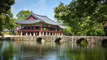 A traditional building with a tiled roof, a stone bridge, and a calm body of water.