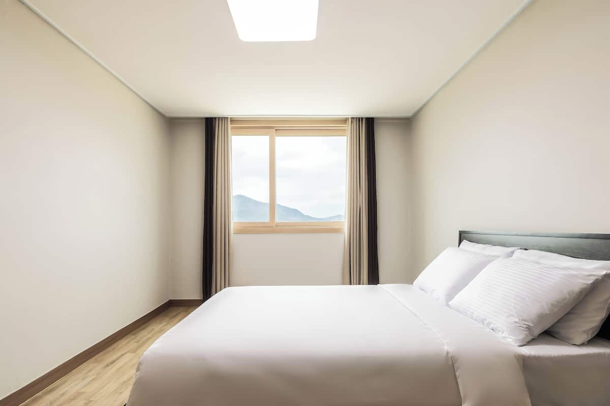 Une chambre d’hôtel avec un lit, une fenêtre avec des rideaux et une vue sur les montagnes.
