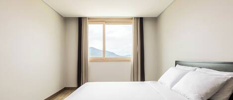Una habitación de hotel con una cama, una ventana con cortinas y vistas a las montañas.