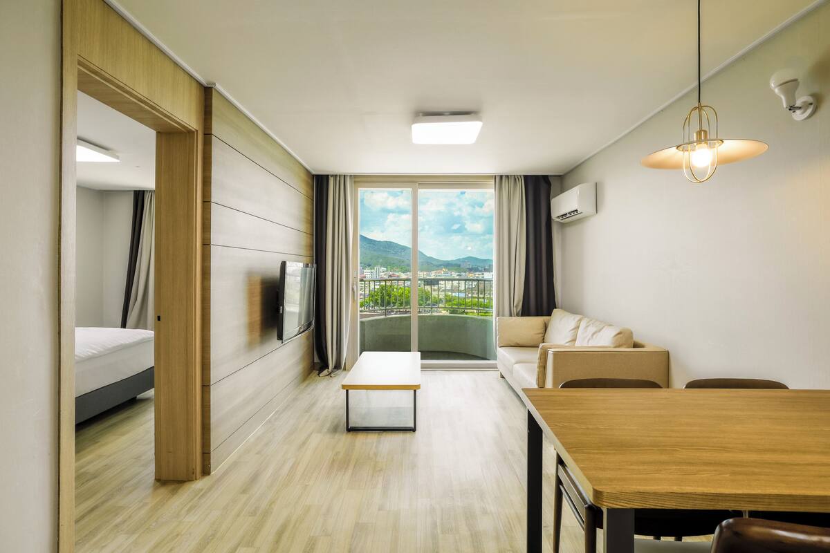 Une chambre d’hôtel moderne équipée d’un lit, d’un canapé, d’une table à manger et d’une grande fenêtre donnant sur la ville.