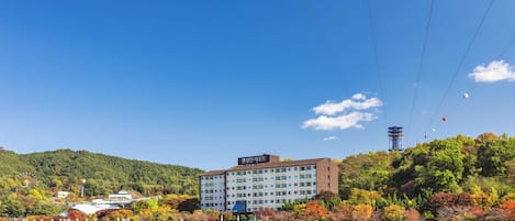 Un hotel de diseño moderno, situado cerca de un cuerpo de agua y rodeado de follaje otoñal.
