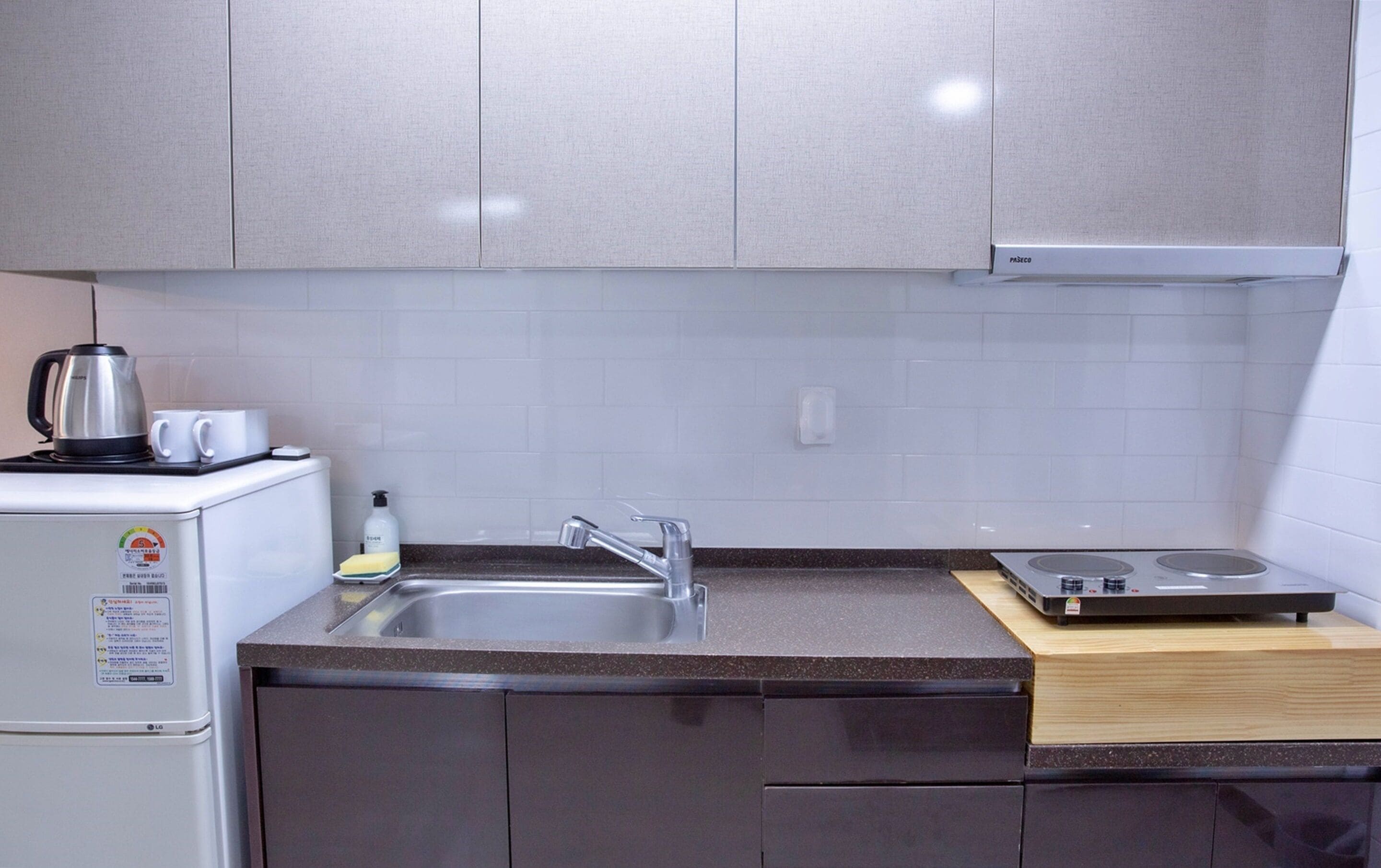 A kitchen with a refrigerator, a coffee maker, a sink, and a stove.