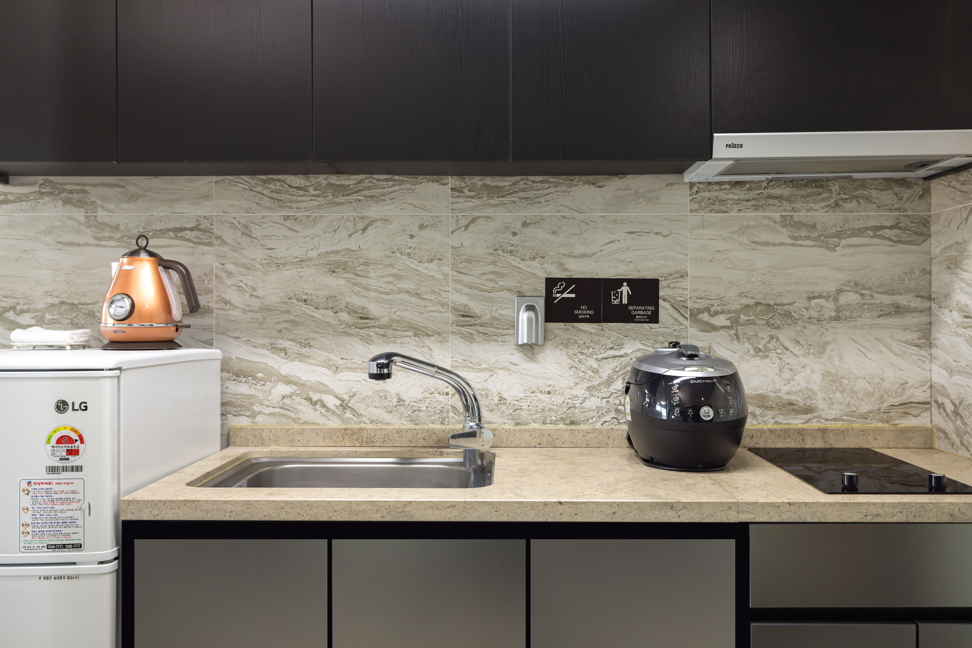 A kitchen with a sink, a kettle, and a rice cooker on the counter.