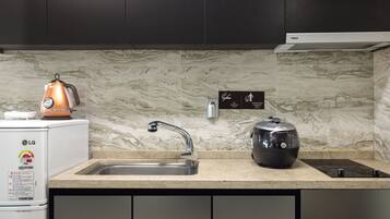 A kitchen with a sink, a kettle, and a rice cooker on the counter.