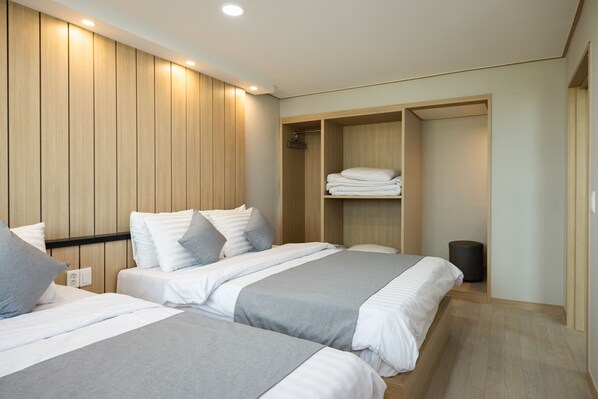 Une chambre d’hôtel moderne avec deux lits, une armoire en bois et une petite poubelle.