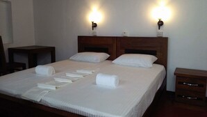 A neatly made bed with white linens and towels, two bedside tables, and wall-mounted lamps. - Mia's Villa (Hikkaduwa)