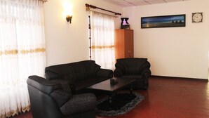 A living room with two black sofas, a coffee table, a wooden cabinet, and a painting on the wall. - Mia's Villa (Hikkaduwa)