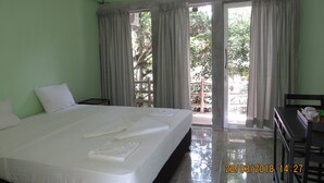 A hotel room with a bed, a desk, and a window with curtains.