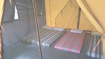 A tent with two beds, each with striped bedding and pillows.
