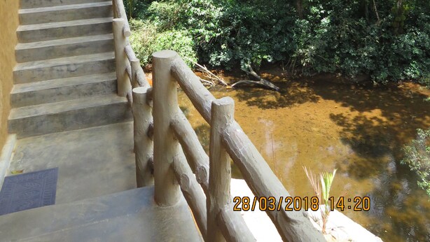 A staircase leading down to a natural area with a wooden railing and a small stream.