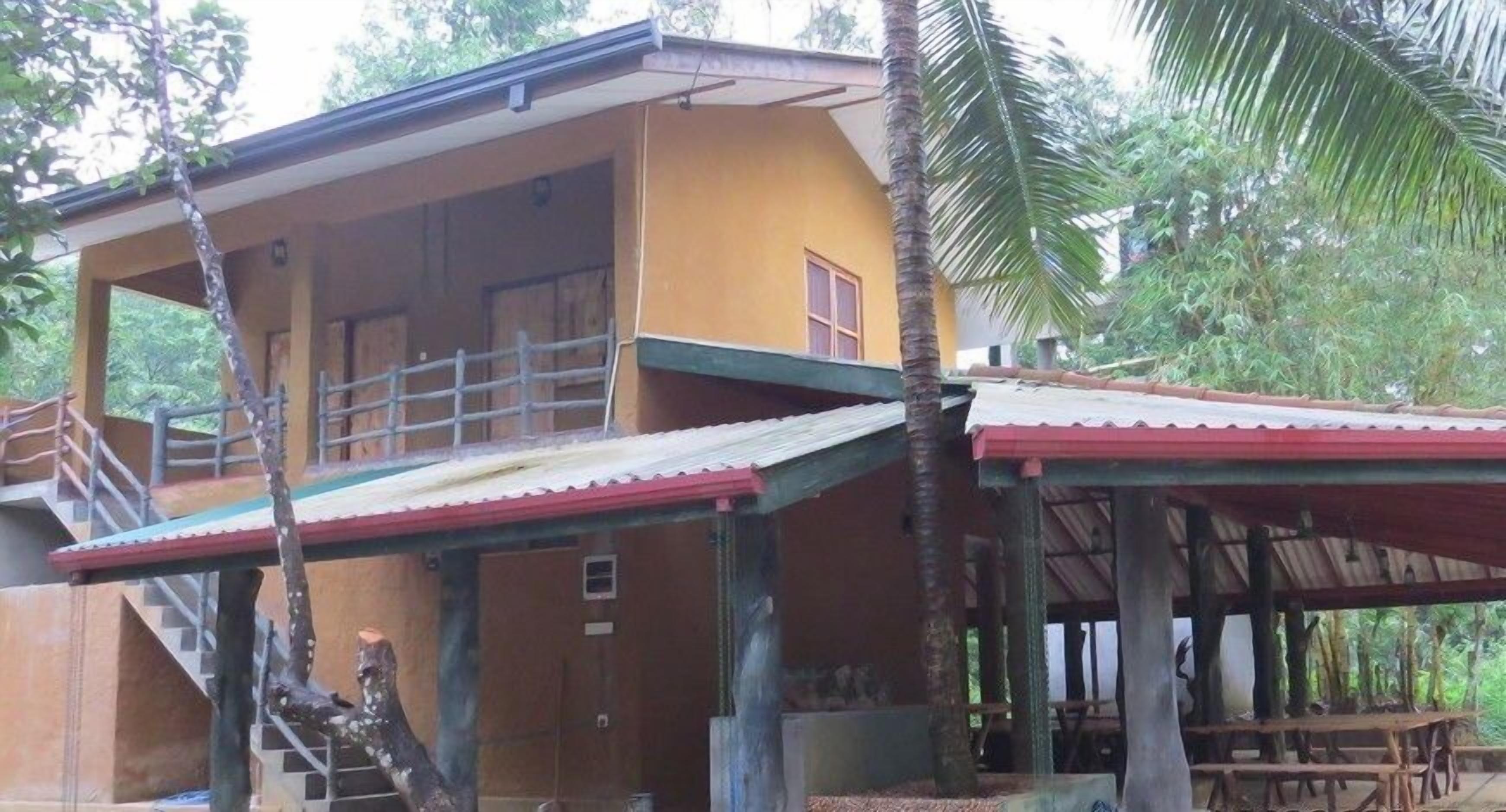 A two-story building with a balcony, wooden railings, and a covered outdoor seating area.