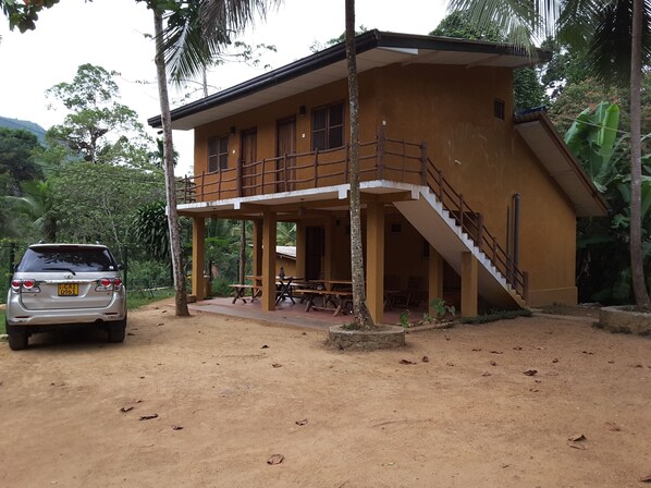 A two-story building with a wooden staircase and a covered porch area.