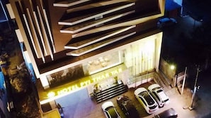 Et moderne hotel med fladt tag, flere balkoner og en godt oplyst indgang.