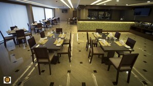 En restaurant med flere spiseborde og stole, et barområde og et fjernsyn på væggen.