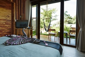 Une chambre avec un lit, une télévision, un hamac et une vue sur l’extérieur.
