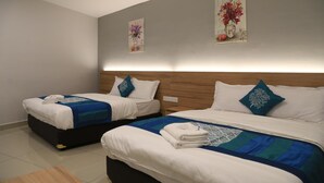 Ein Hotelzimmer mit zwei Betten, jeweils mit blauer und weißer Bettdecke, weißen Kissen und einem Holz-Kopfteil. An der Wand hängen zwei Gemälde mit Blumenmotiven.