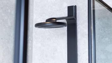 Een moderne, minimalistische douche met een strak zwart design, gemonteerd op een gestructureerde wand.