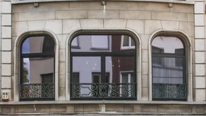 Un edificio de varios pisos con ventanas arqueadas y barandillas de hierro decorativas.