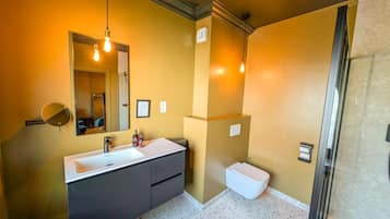Une salle de bain moderne avec un grand miroir, un lavabo blanc, des meubles sombres et des toilettes blanches.