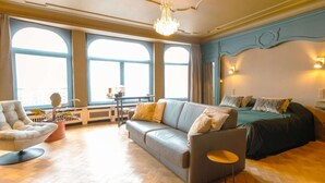Una habitación amplia con un gran ventanal, un sofá, una silla y una cama.