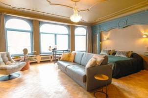 Una habitación amplia con un gran ventanal, un sofá, una silla y una cama.