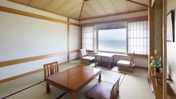 Ein traditioneller japanischer Raum mit Tatami-Böden, einem niedrigen Holztisch und Meerblick.