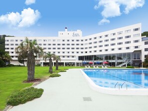 Un hotel con piscina, mobiliario de exterior y palmeras.
